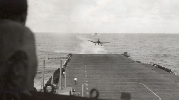 "A Navy Grumman F6F lands on its carrier following a strike at Japanese installations in the Phillipines" on February 6, 1945. Gift of Charles Ives.