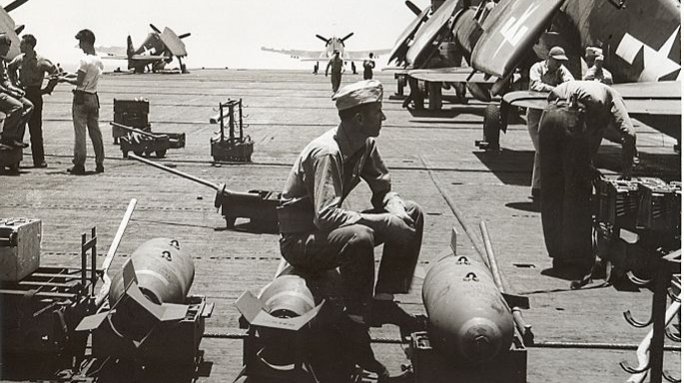 Rearming Hellcats on the deck of an aircraft carrier. Gift in memory of John Valdemor Peterson.
